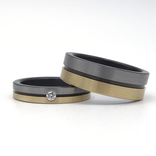 Lines ringenset van zirkonium en geelgoud – moderne ringen met strak lijnenspel en subtiele diamant in de damesring.

