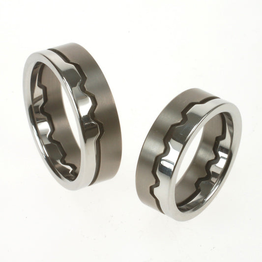 Trouwringen van titanium, zirkonium en staal met een middenlijn in morsecode, gebaseerd op initialen