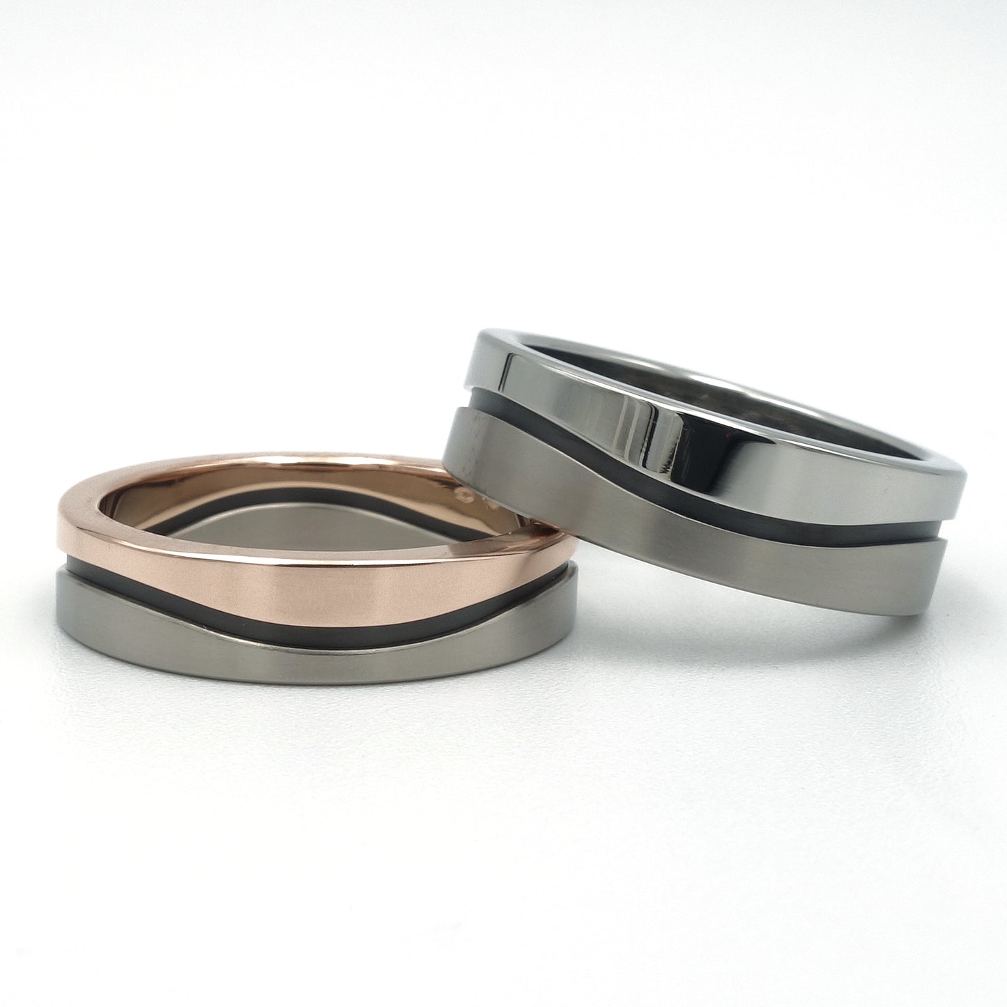 Set van twee Nauta Golf ringen met golvende lijn in mat titanium en zwart zirkonium, één met 18kr roodgoud, één met edelstaal