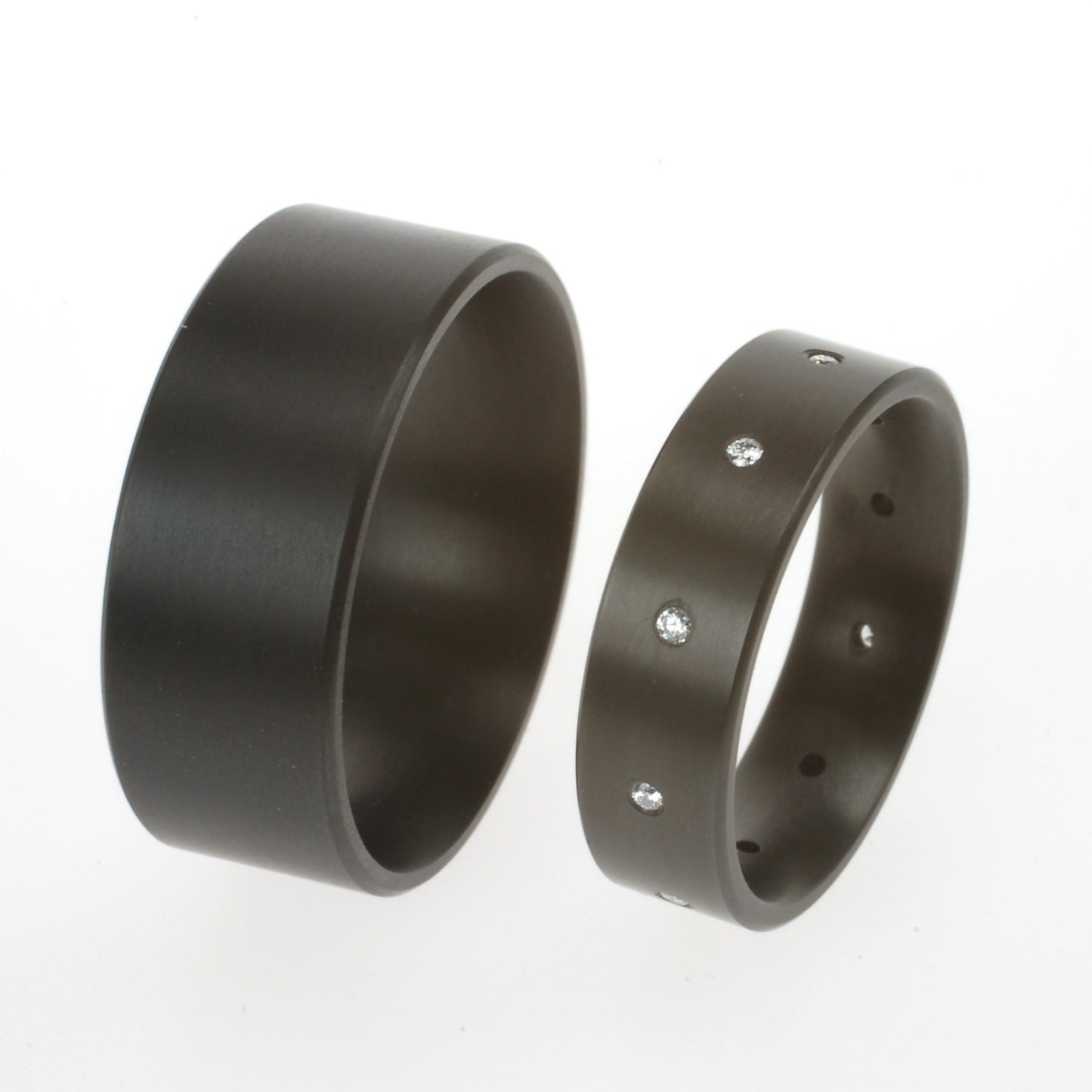 Zwarte zirkoniumringen; één met 10 verzonken diamanten van 0.01ct, één zonder steen