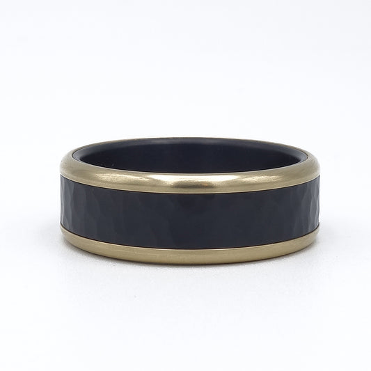 Ring van zwart zirkonium met hamerslag en een rand van 14 karaat geelgoud. Stoere, luxe uitstraling.