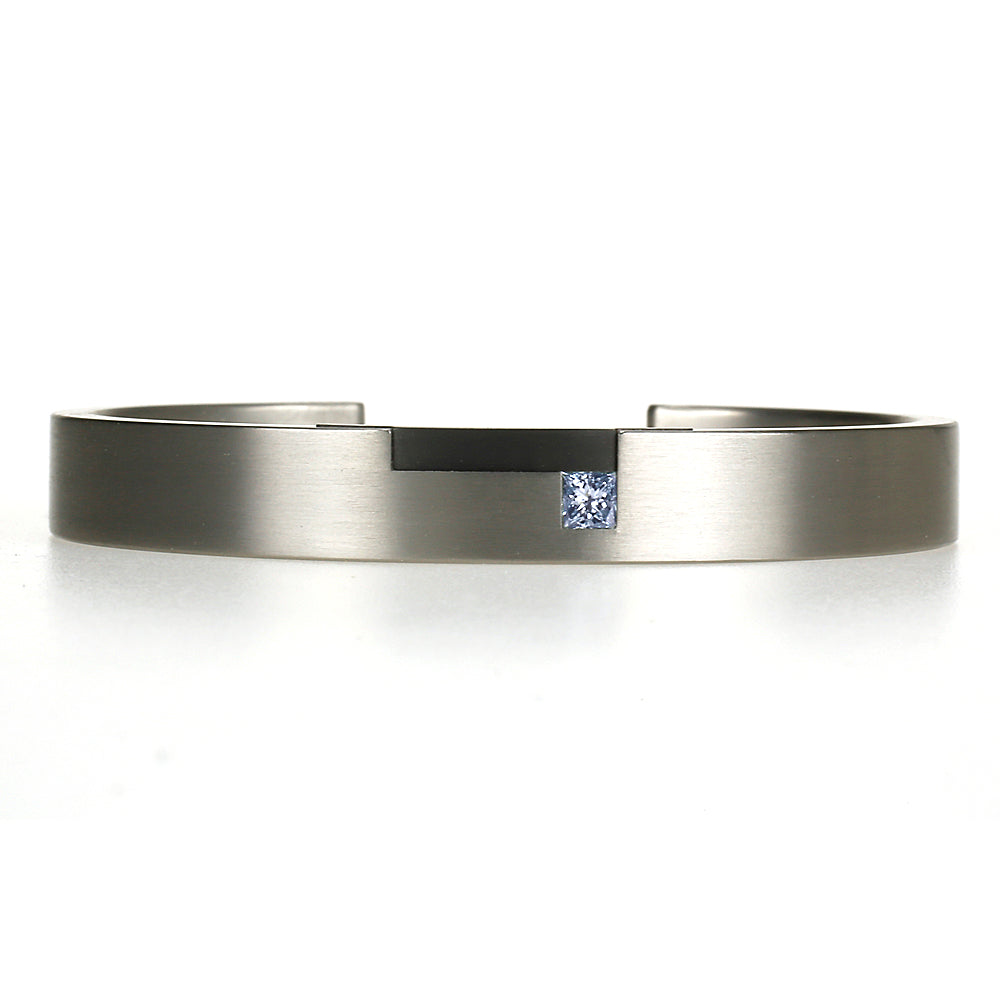 Strakke titanium armband met blauwe prinsesgeslepen diamant en zwart zirkonium detail, moderne maatwerkarmband.