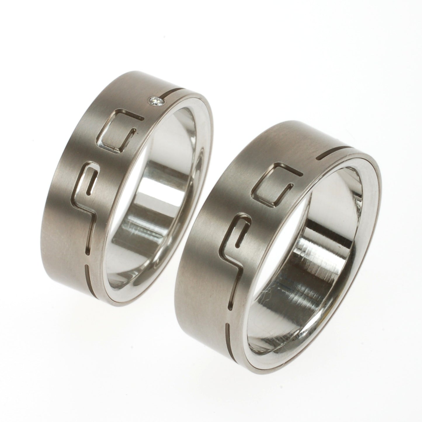 Trouwringen in twee lagen titanium met uitgesneden initialen en diamant