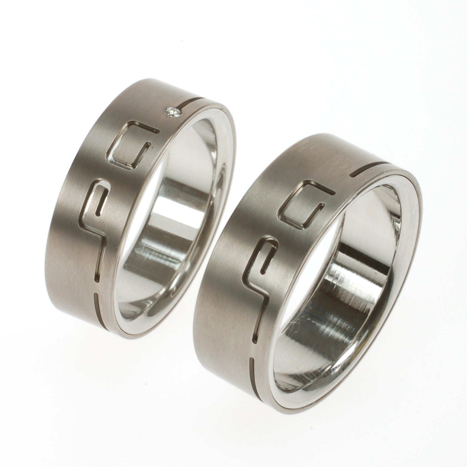 Trouwringen in twee lagen titanium met uitgesneden initialen en diamant