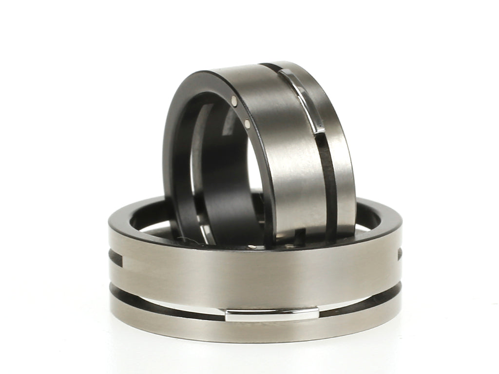 Set Split-Level ringen van zirkonium en edelstaal – moderne combinatie van donker en licht met verdiept lijnenspel.

