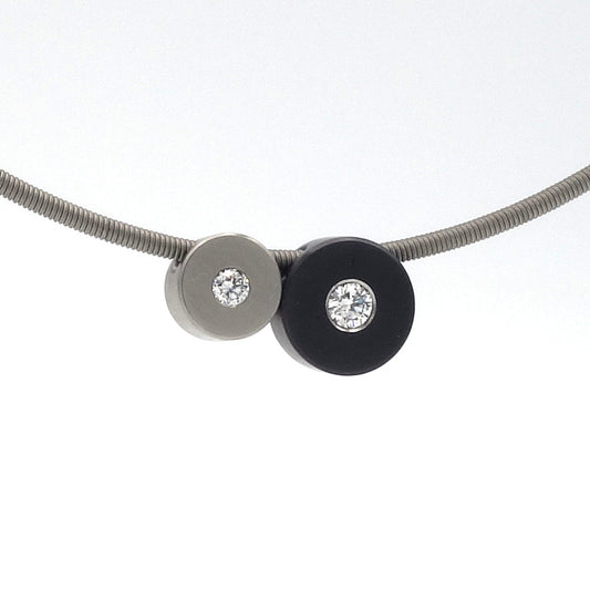 Hangercombinatie van zwarte zirkoniumschijf (8,5 mm, 0,08 ct diamant) en titaniumschijf (6,5 mm, 0,03 ct diamant) aan een metalen spang.

