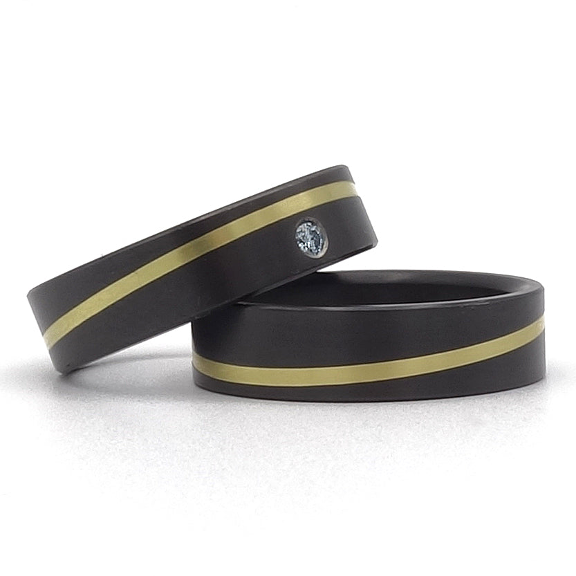 Zwarte ringen met een diagonale lijn van geelgoud. Eén van de ringen is met een diamant