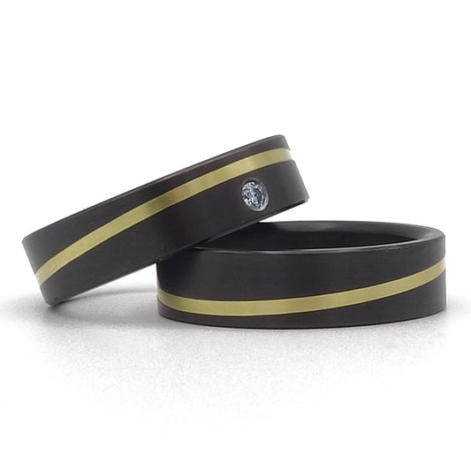 Zwarte ringen met een diagonale lijn van geelgoud. Eén van de ringen is met een diamant