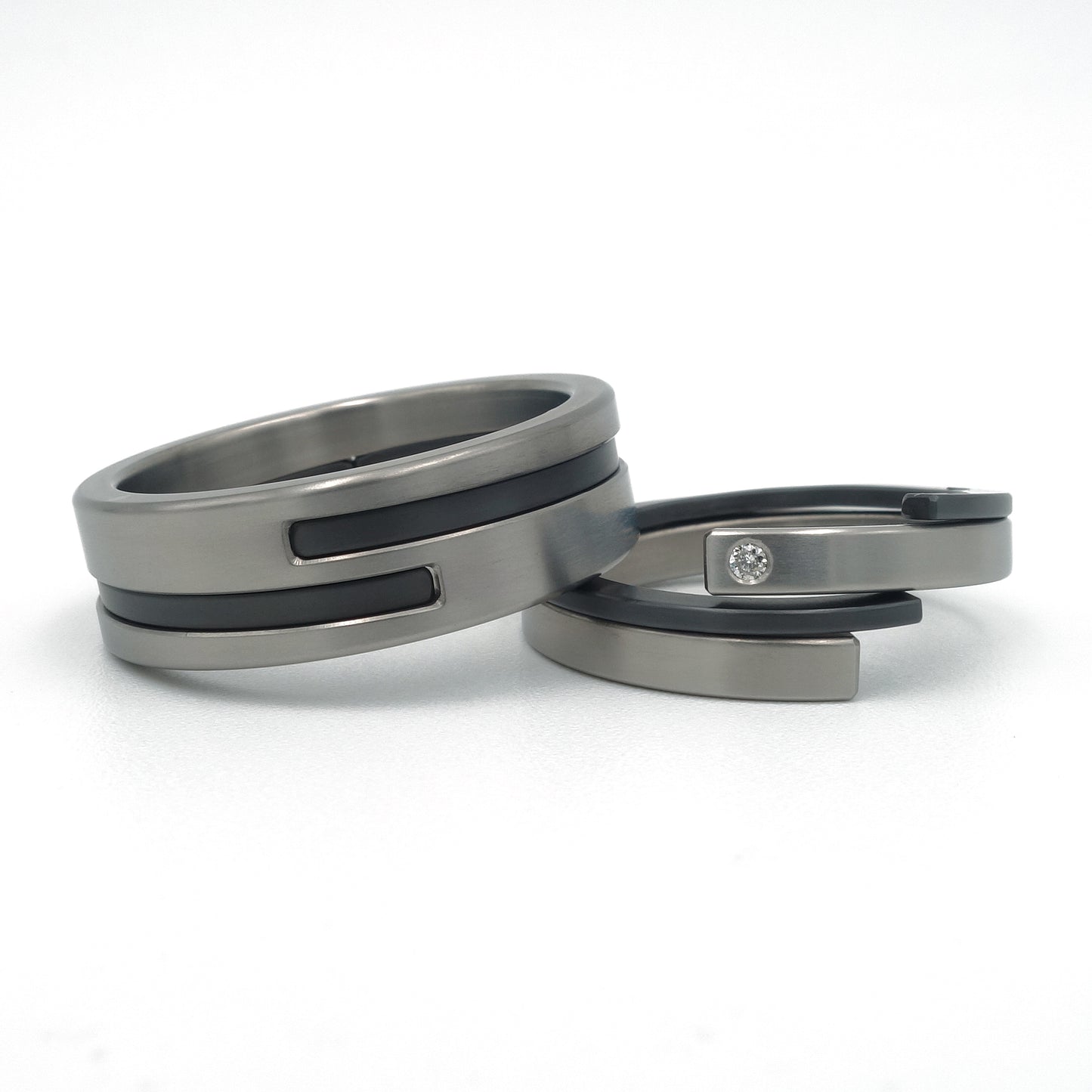 “Set moderne Adam-Eva ringen van titanium en zwart zirkonium met diamant 0.015ct”