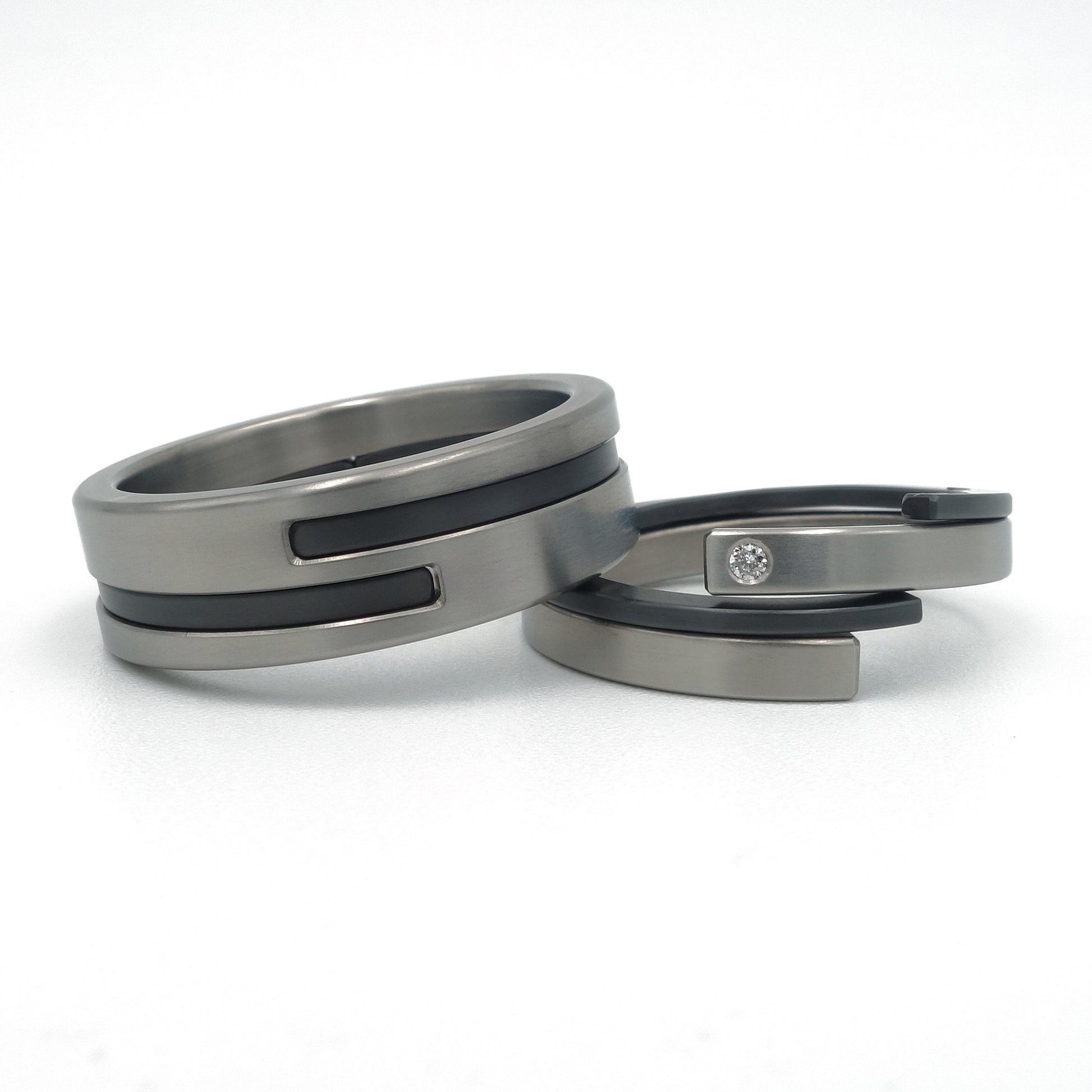 “Set moderne Adam-Eva ringen van titanium en zwart zirkonium met diamant 0.015ct”
