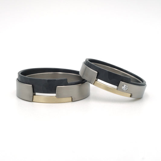 Moderne trouwringen met titanium basis, zwart zirkonium met hamerslagstructuur en 14kr geelgoud, één ring met diamant.