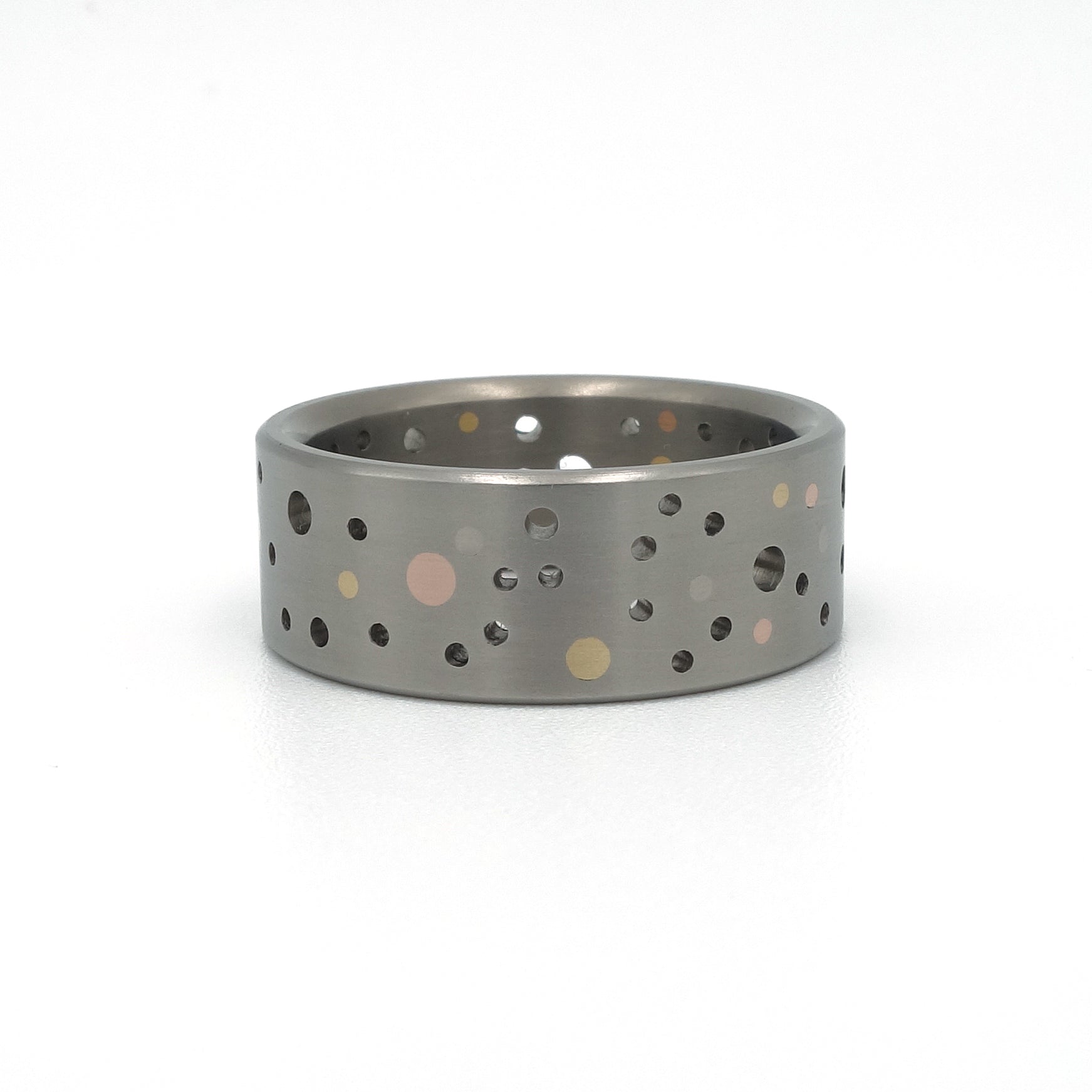 Titanium Confetti-ring met willekeurig gatenpatroon en gouden en platina stippen.