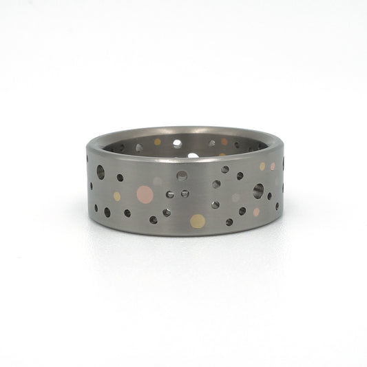 Titanium Confetti-ring met willekeurig gatenpatroon en gouden en platina stippen.
