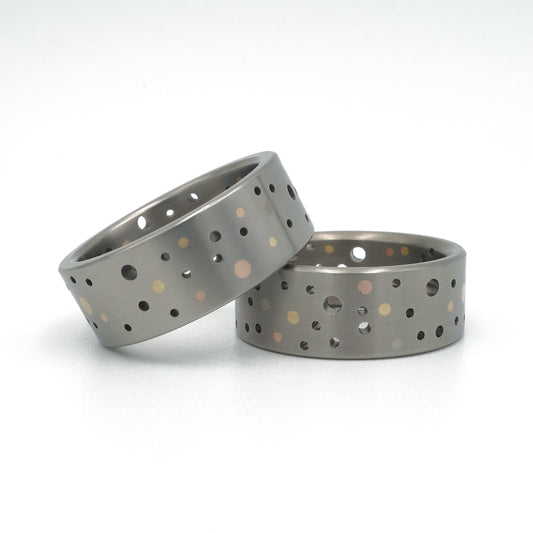 Set titanium Confetti-ringen met gouden en platina stippen in willekeurig gatenpatroon.