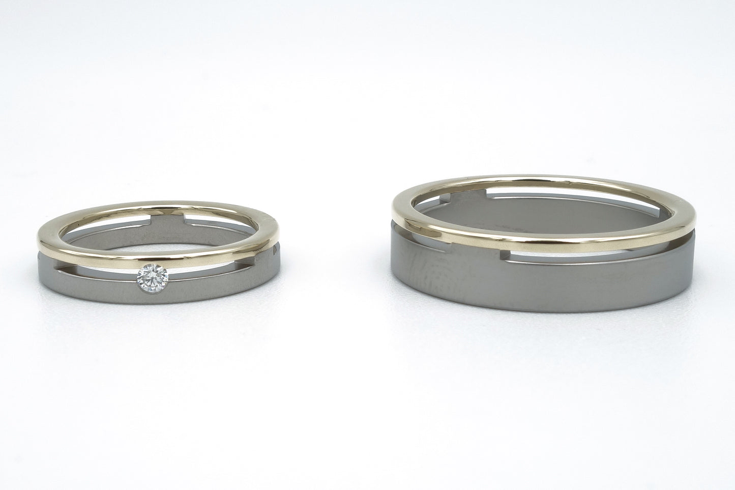 Brede titanium trouwringen met gele gouden rand. Damesring met 0.05ct diamant, robuuste herenring.