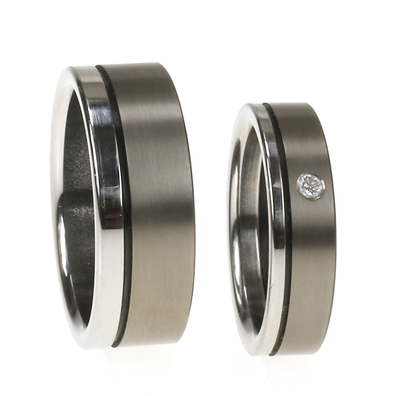 Twee trouwringen van edelstaal en zirkonium; één met diamant, één zonder, samen gepresenteerd als trouwset.