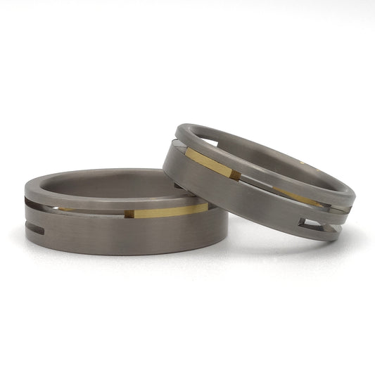 Split-Level ringenset van titanium en geelgoud – moderne trouwringen met verdiept lijnenspel en warm gouden contrast.

