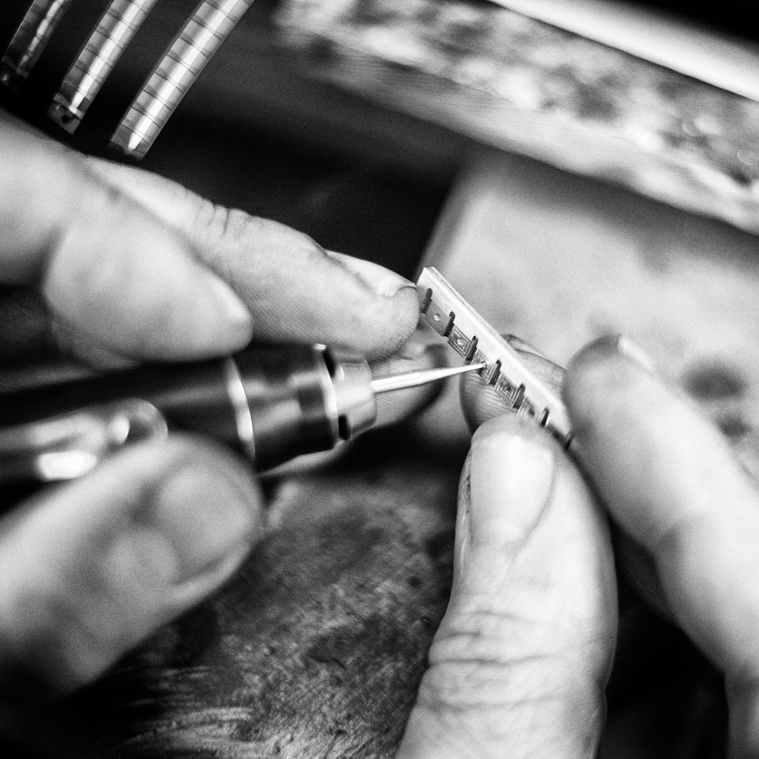 Wouter Dijkman schuurt een sieraadonderdeel af – zwart-witfoto van het fijne slijpwerk in het atelier.

