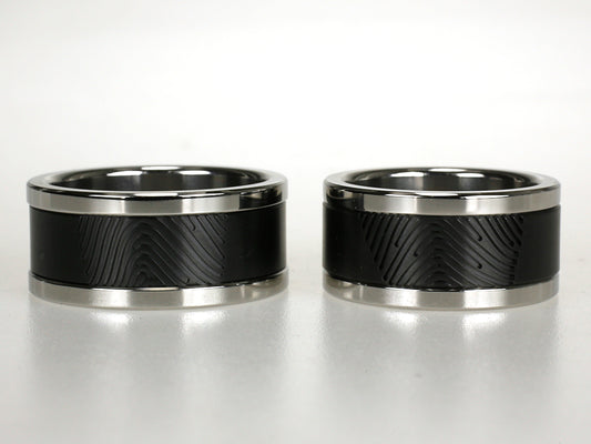 Stoer ring van zwart zirkonium met vingerafdruk en hoogglanzende titanium randen.
